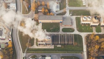 a birds eye view of a factory releasing a lot of smoke and negatively affecting climate change.