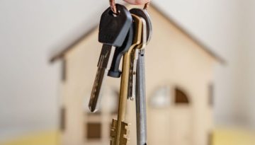 House keys in front of a model of a house to resemble somebody growing their property portfolio.
